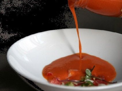 Salsa de naranja vertida en un tazón blanco sobre una pequeña ensalada o aperitivo.