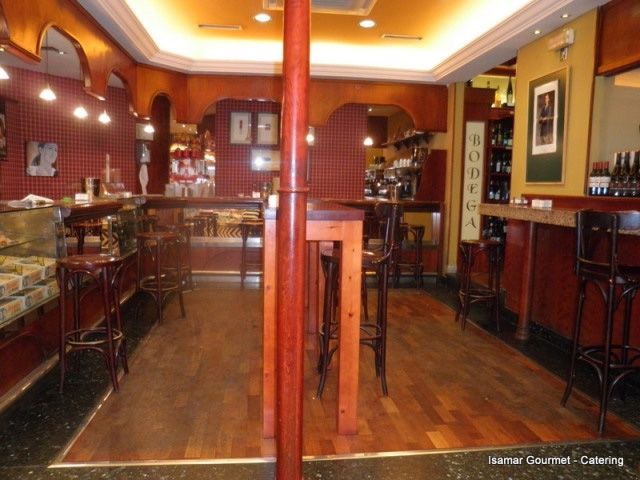 Interior de bar elegante y vacío con iluminación cálida, paneles de madera y taburetes altos a lo largo de la barra.