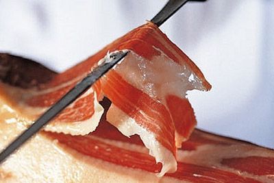 Cortar lonchas finas de jamón curado con dos pinzas metálicas.