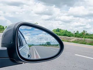 Un coche circula por una carretera con un espejo retrovisor.
