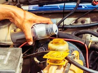 Una persona está vertiendo aceite en una botella de líquido de frenos.