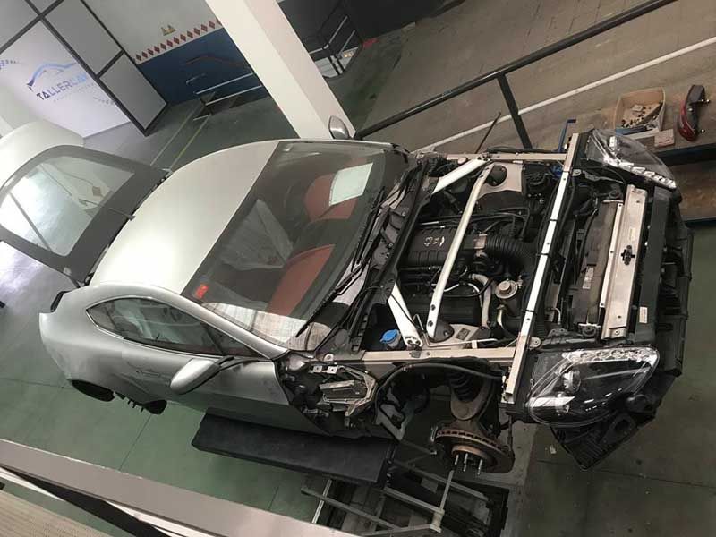 Un coche con el capó abierto está estacionado en un garaje.