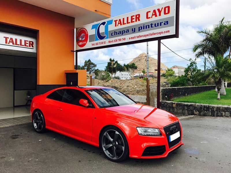 Un coche rojo está aparcado frente a un cayo más alto.