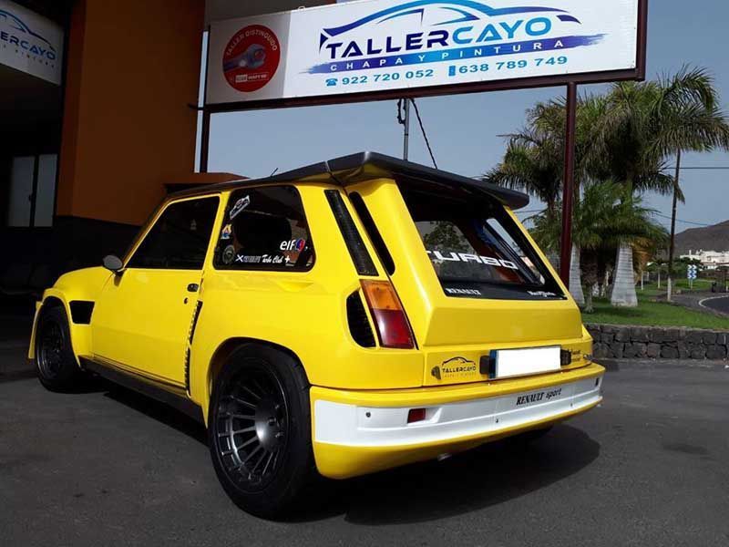 Un coche amarillo está estacionado frente a tallercayo