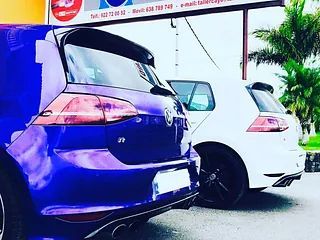Un coche azul y uno blanco están aparcados uno al lado del otro en un aparcamiento.