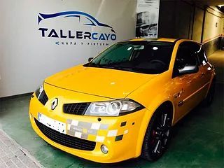 Un coche amarillo está estacionado frente a tallercayo.