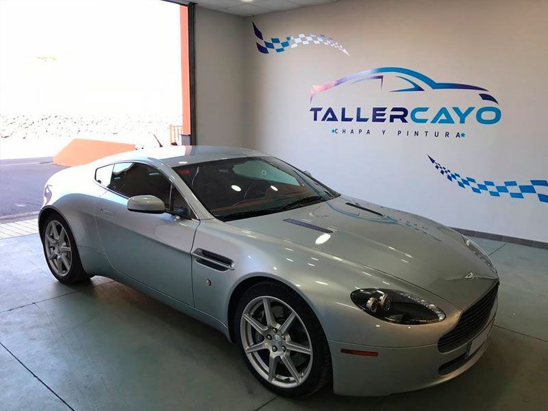 Un coche deportivo plateado está aparcado frente a tallercayo.