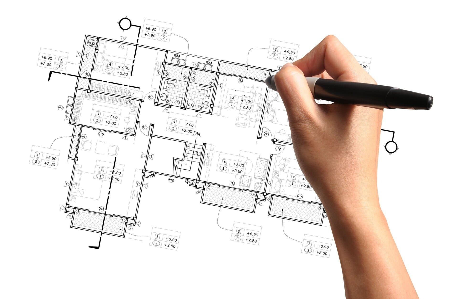 Una persona está dibujando un plano de una casa con un bolígrafo.