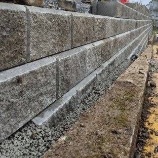 Graue Betonstützmauer mit Kiesbett, terrassenförmig angelegt.