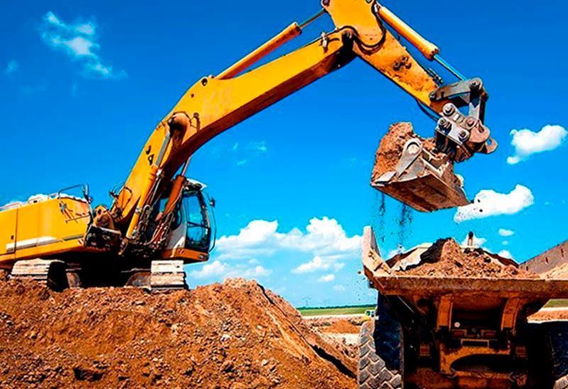 Una excavadora amarilla está cargando tierra en un camión volquete.