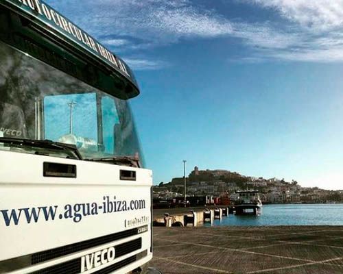Un camión Iveco blanco está estacionado frente a un cuerpo de agua.