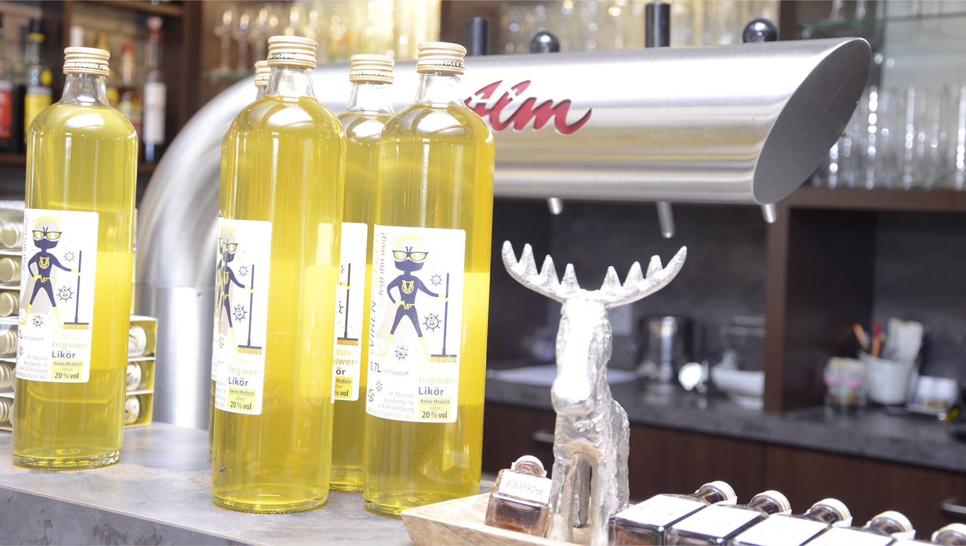 Mehrere Flaschen mit Flüssigkeit stehen auf einer Theke neben einer Elchstatue.