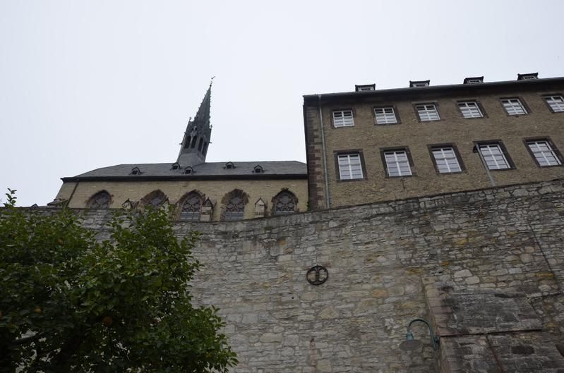Neben einer Steinmauer steht ein Gebäude mit einem Kirchturm darauf.