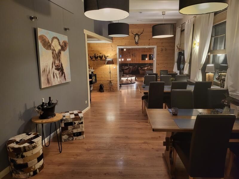 Ein Esszimmer mit Tischen und Stühlen und einem Gemälde einer Kuh an der Wand.