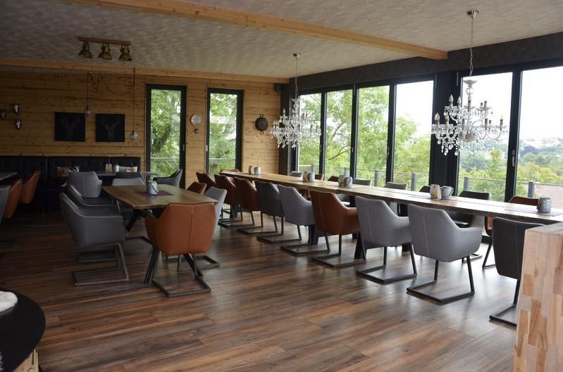 Ein großes Esszimmer mit Tischen und Stühlen und vielen Fenstern.