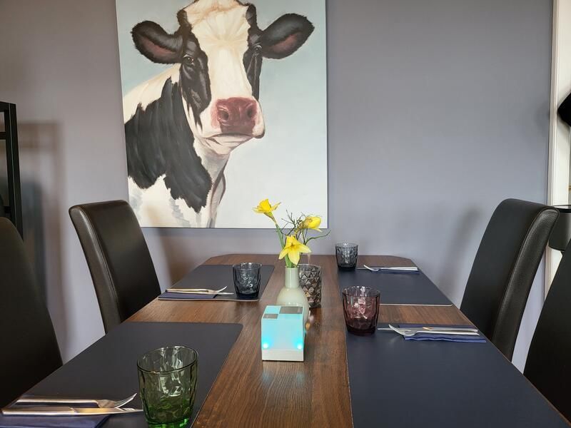 Ein Esstisch mit einem Gemälde einer Kuh an der Wand darüber