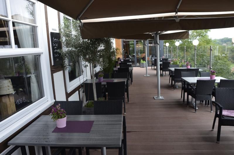 Eine Terrasse mit Tischen und Stühlen unter Sonnenschirmen