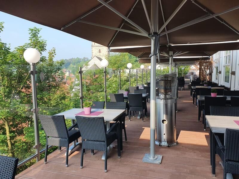 Eine Terrasse mit Tischen und Stühlen unter Sonnenschirmen