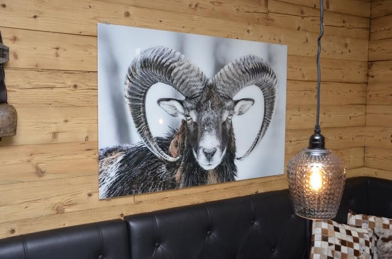 Ein Bild von einem Widder mit Hörnern hängt an einer Holzwand