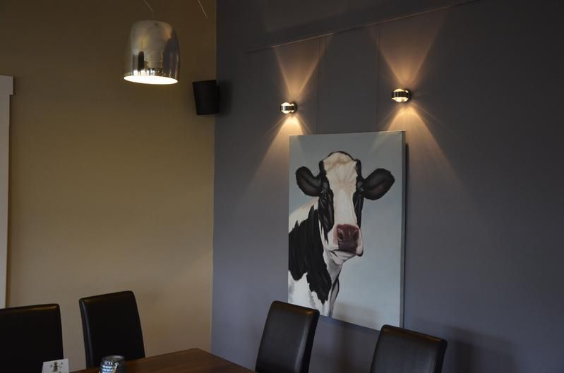 Ein Gemälde einer Kuh hängt an einer Wand über einem Esstisch