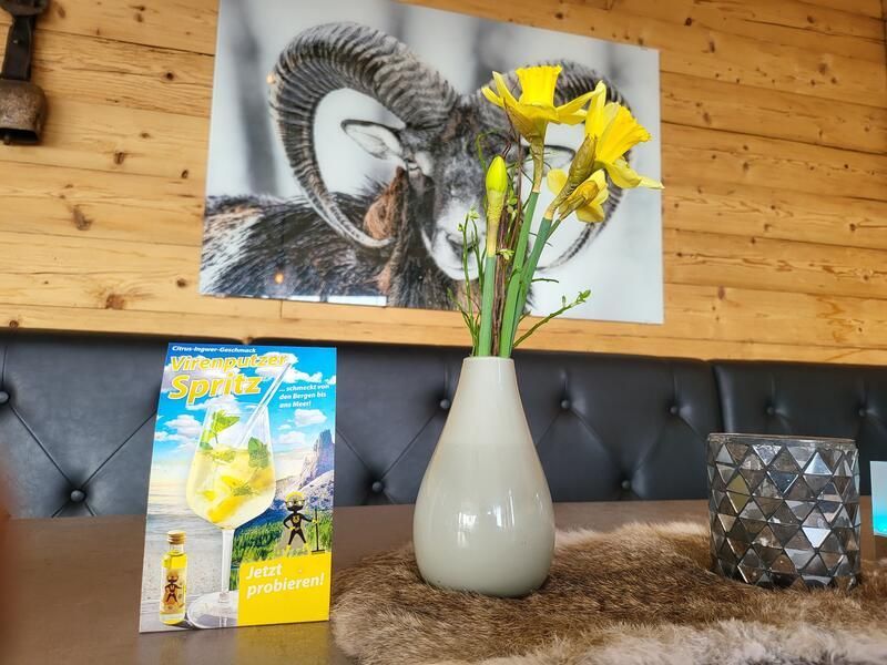 Eine Vase mit Blumen steht auf einem Tisch vor einem Gemälde eines Widders