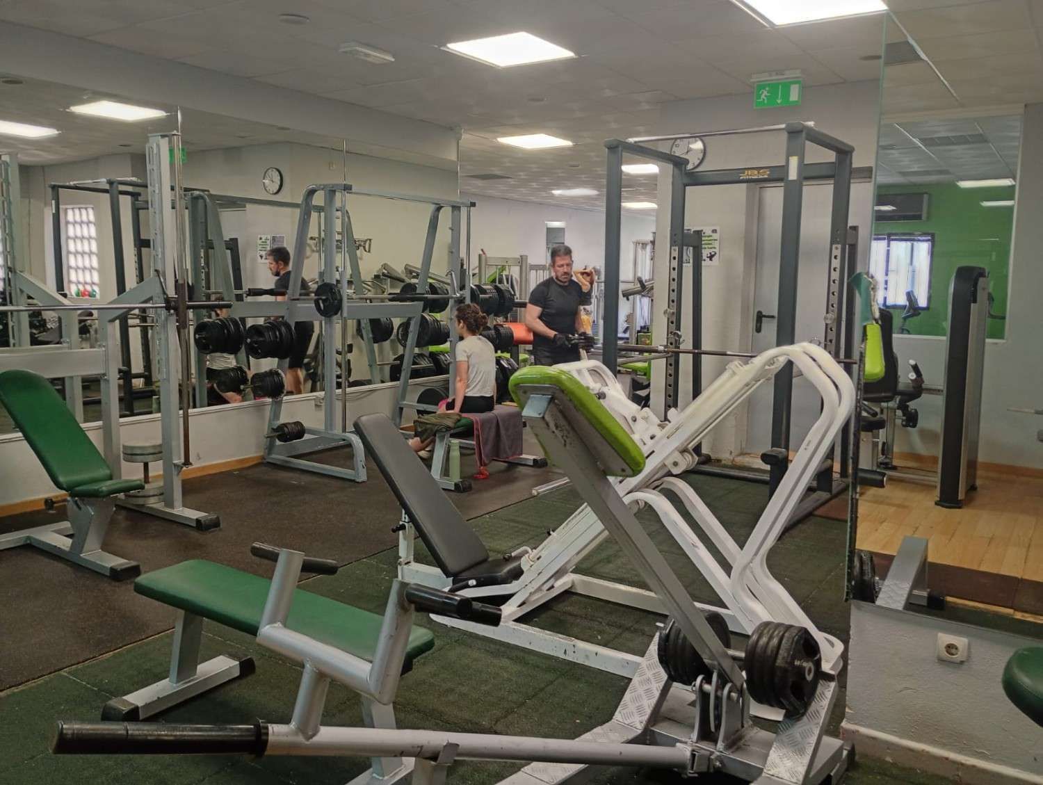 Un gimnasio luminoso y espacioso con máquinas de pesas, bancos y pesas 