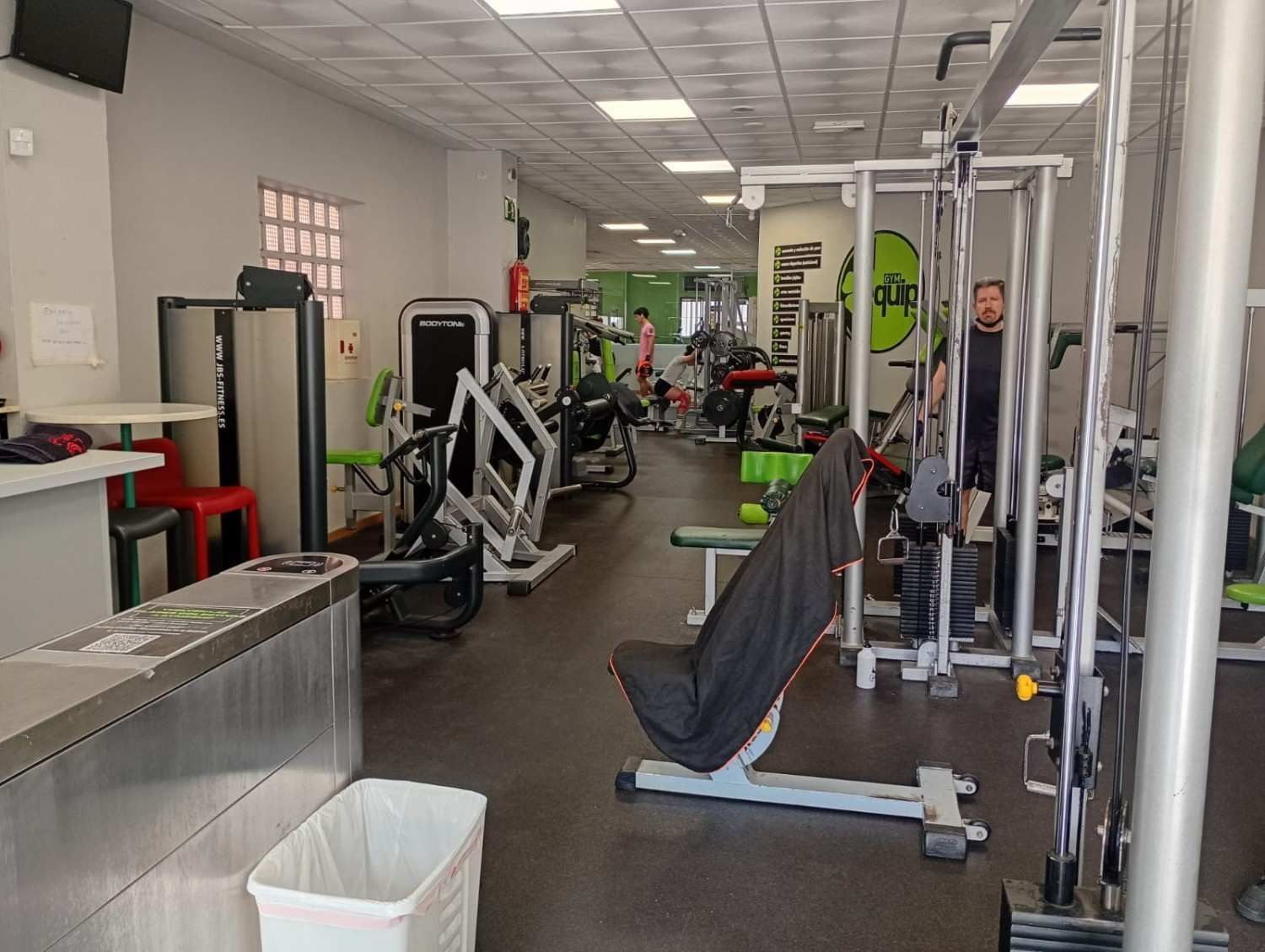 El interior de un gimnasio con varias máquinas de pesas, una recepción 