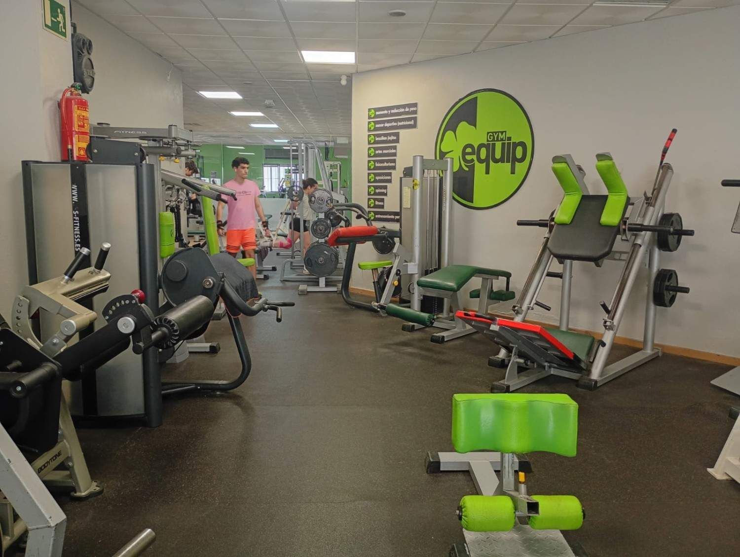 El interior de un gimnasio con varias máquinas de ejercicio en color negro 