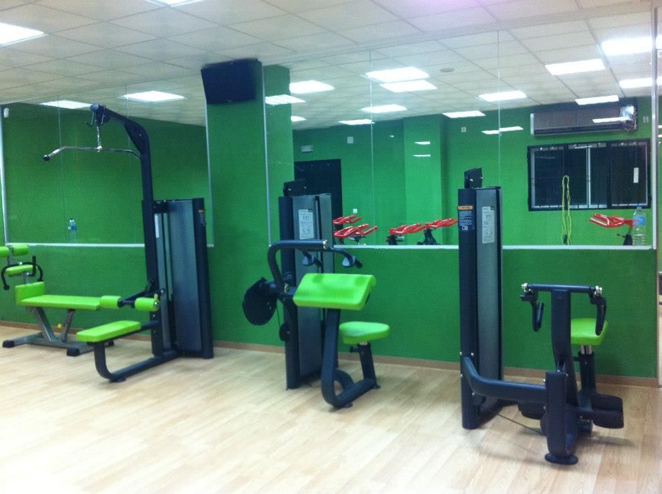 Un gimnasio con tres máquinas de ejercicio con detalles en verde