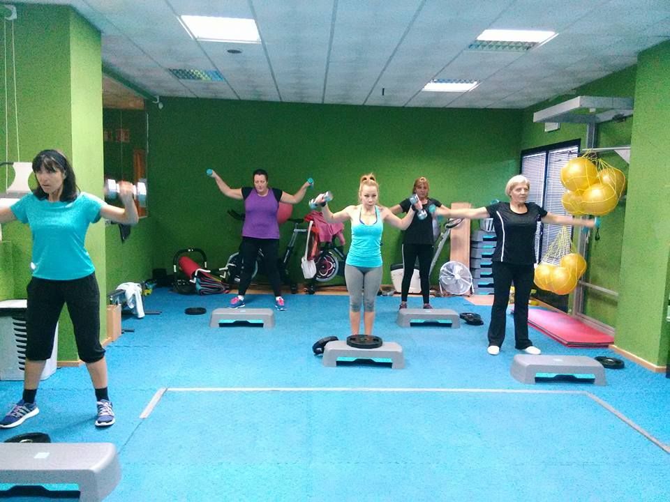 Cinco personas en una clase de ejercicios realizan elevaciones 