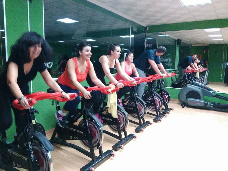 Cuatro personas hacen ejercicio en bicicletas estáticas en un gimnasio 