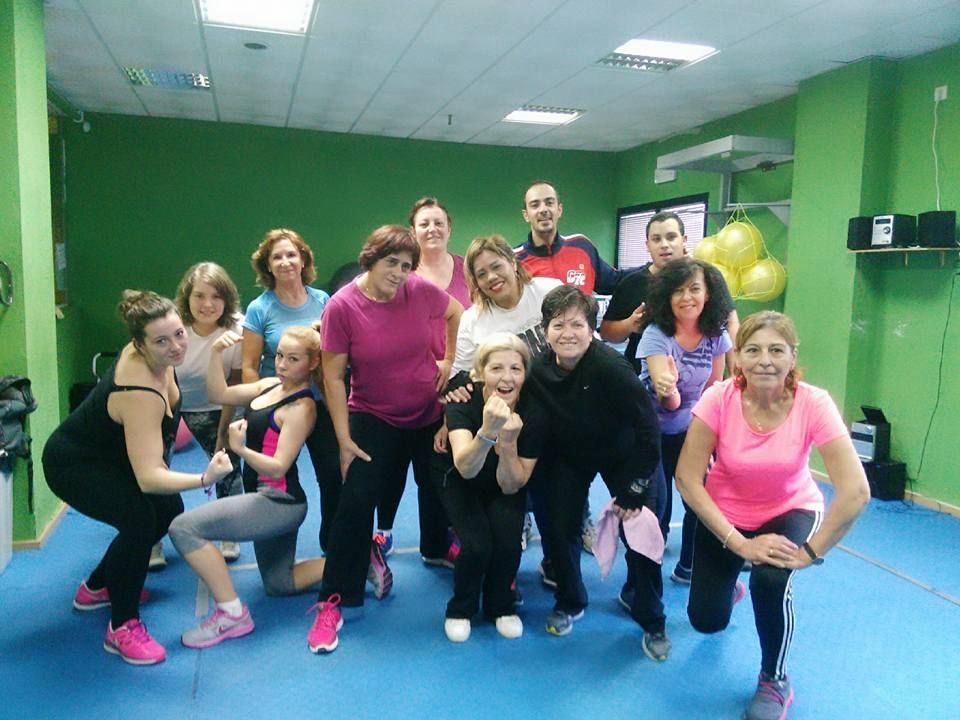 Un grupo de personas posa en un gimnasio de color verde brillante, 