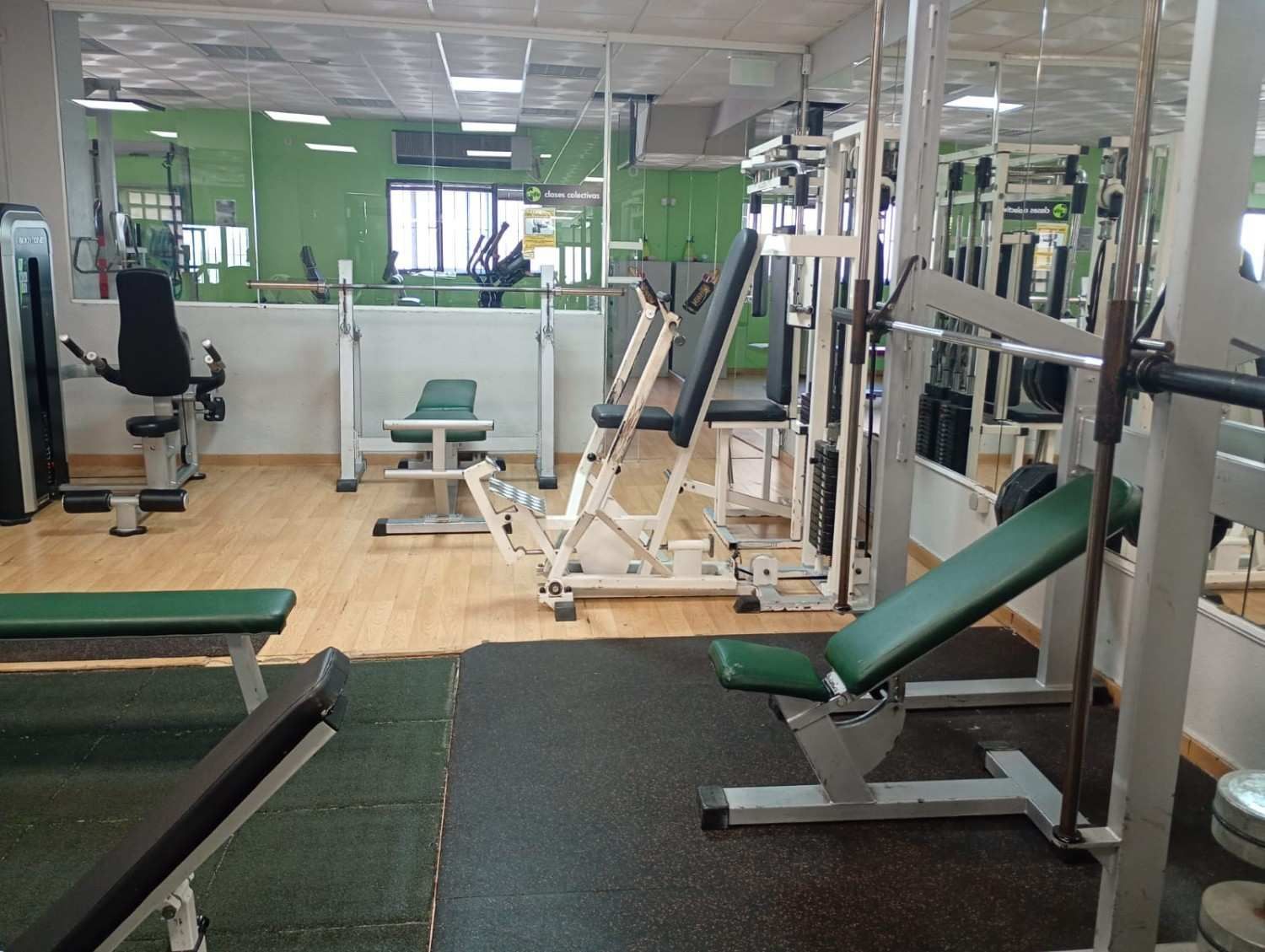 El interior de un gimnasio con varias máquinas de ejercicio, bancos de pesas