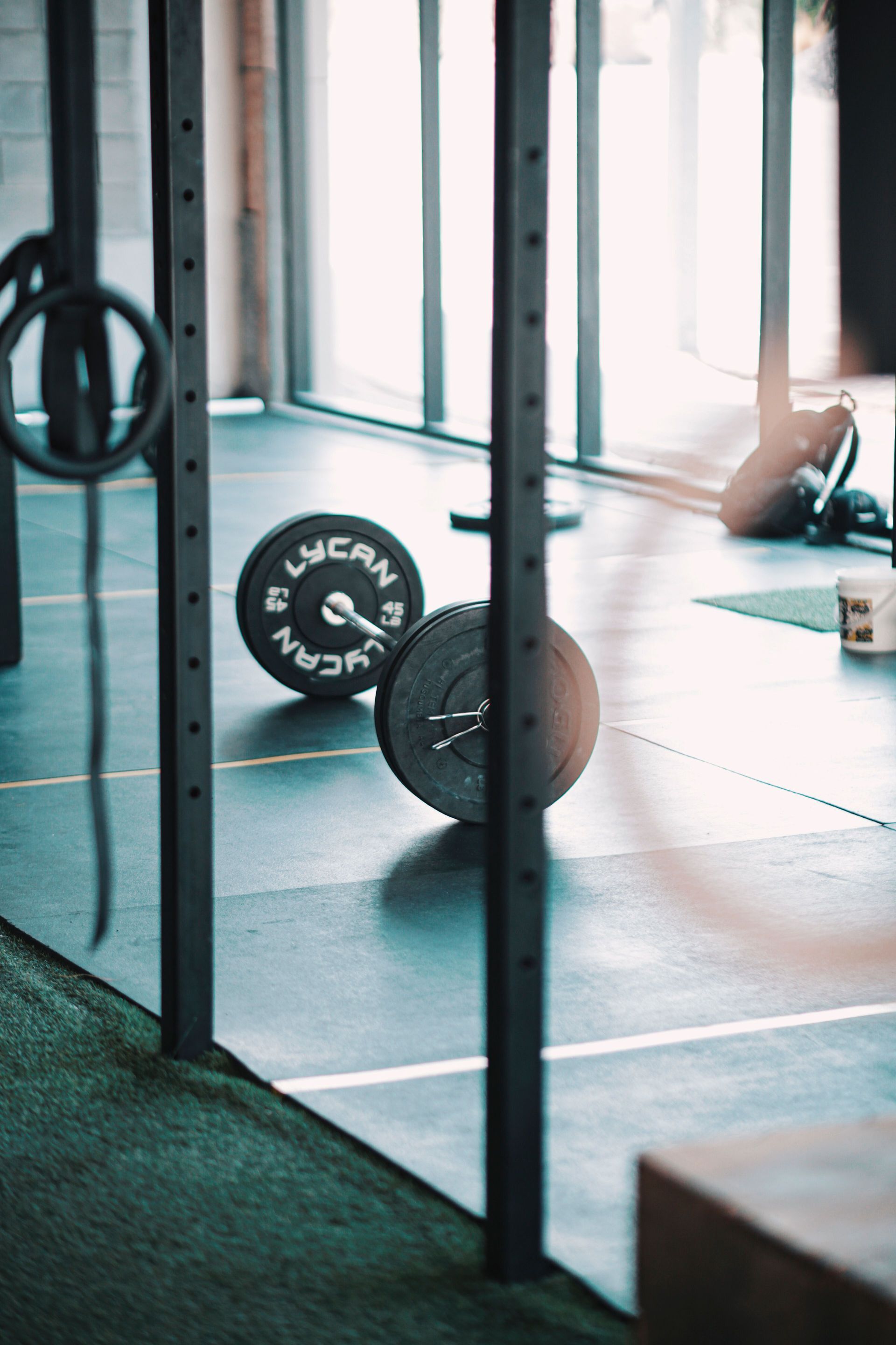 Pesas de gimnasio y una barra en el luminoso suelo de un estudio cerca de grandes ventanas.