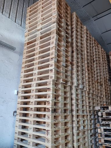 Un almacén lleno de montones de paletas de madera apiladas unas sobre otras.