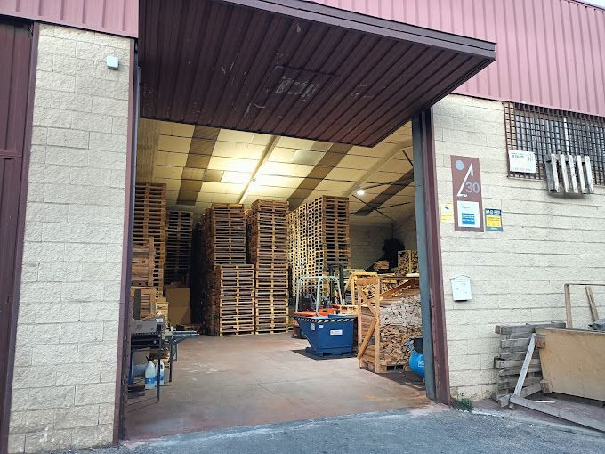 Un gran almacén con muchos palets de madera en su interior.