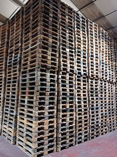 Un almacén lleno de montones de paletas de madera apiladas unas sobre otras.