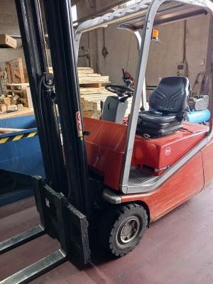 Una carretilla elevadora roja está estacionada en un almacén.