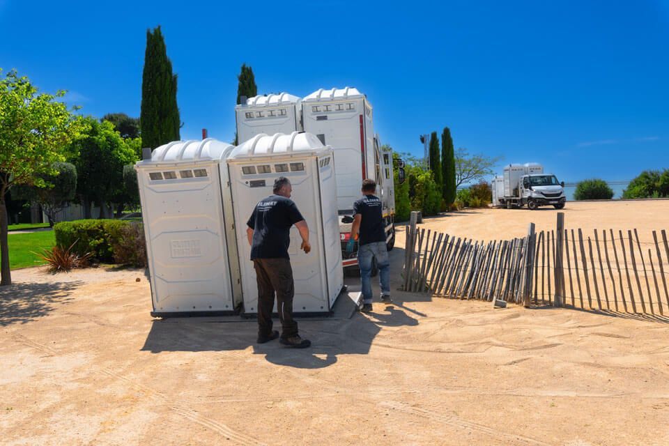 Nos techniciens qui installent des toilettes dans un terrain sablé