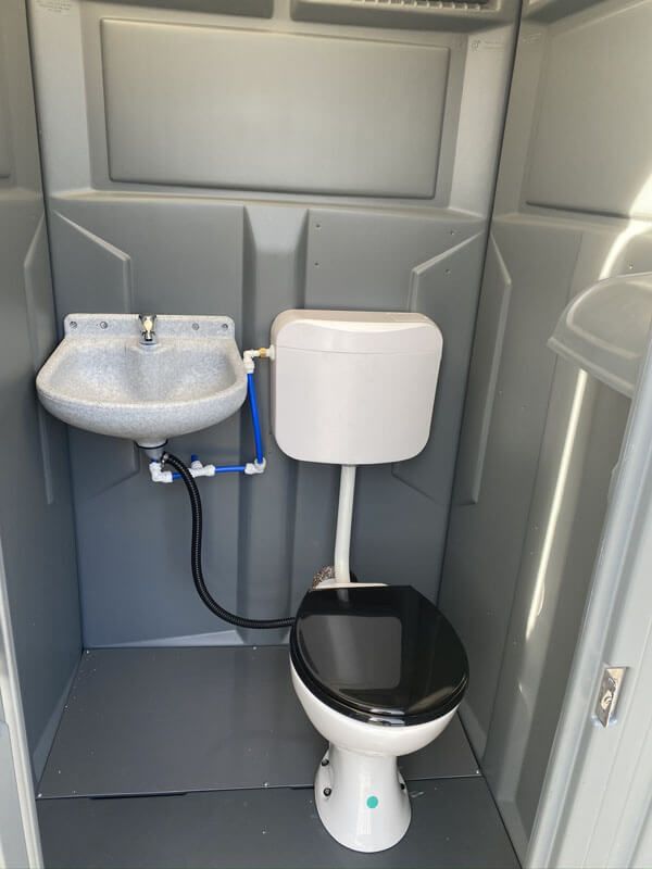 Un employé qui installe des cabines de toilette en pleine nature