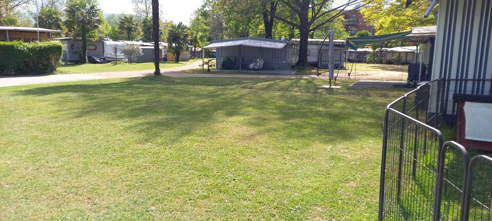 Un grande campo erboso con un recinto in primo piano e una tenda sullo sfondo.