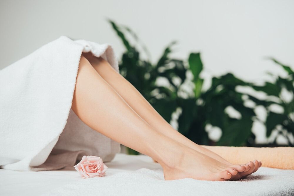 Una mujer está acostada en una cama con las piernas envueltas en una toalla.