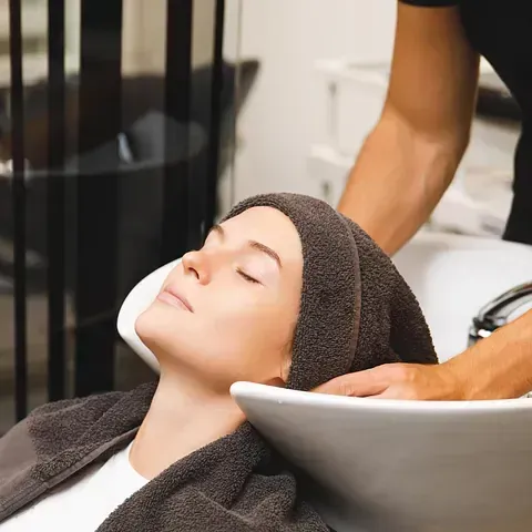 Una mujer se lava el cabello en un lavabo de una peluquería.
