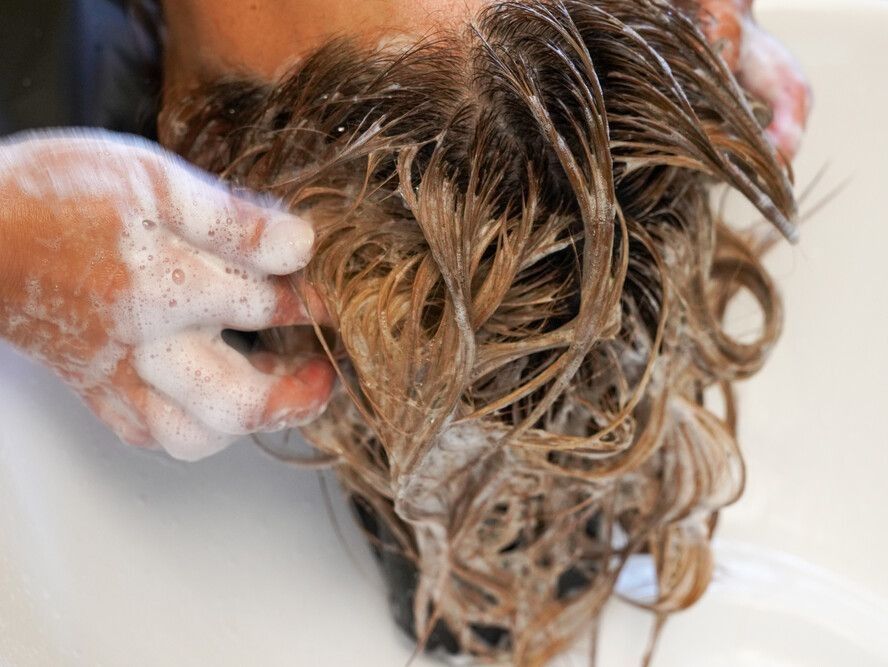 Una mujer se lava el cabello en un lavabo.