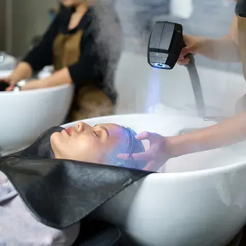 Una mujer se lava el cabello en un lavabo de una peluquería.