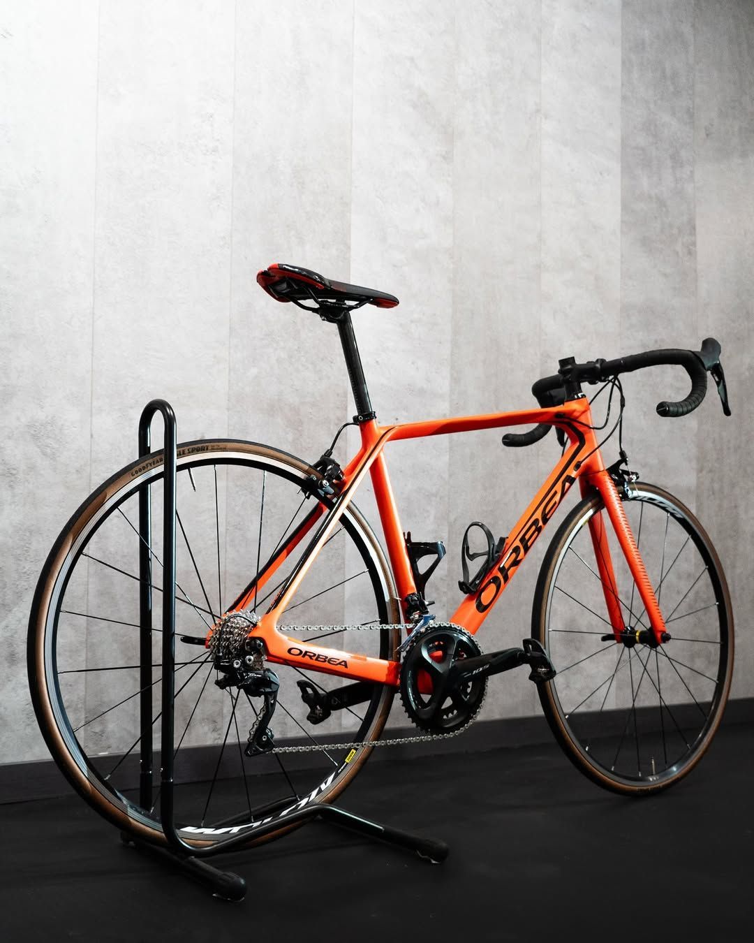 Una bicicleta Orbea naranja está estacionada en un soporte