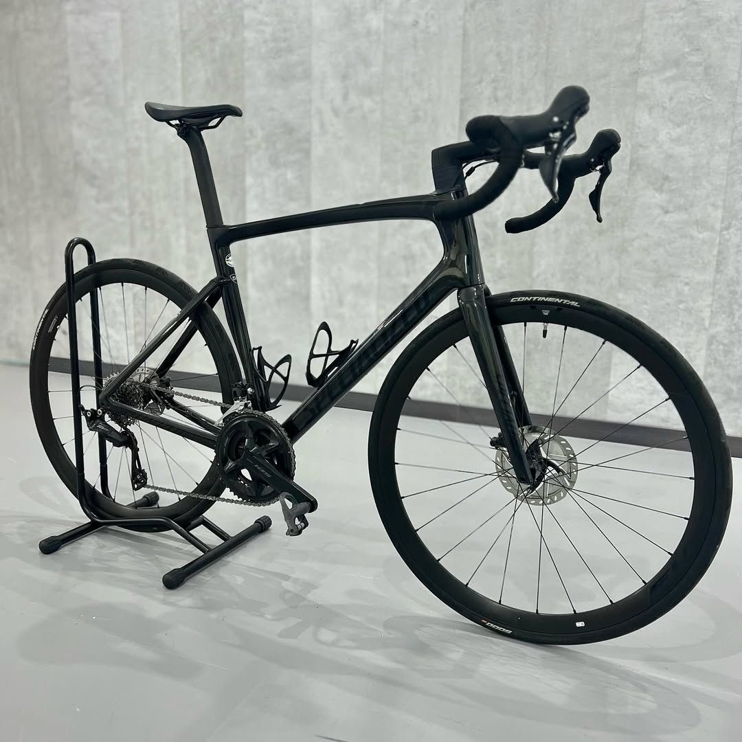 Una bicicleta negra está estacionada en un soporte en una habitación.
