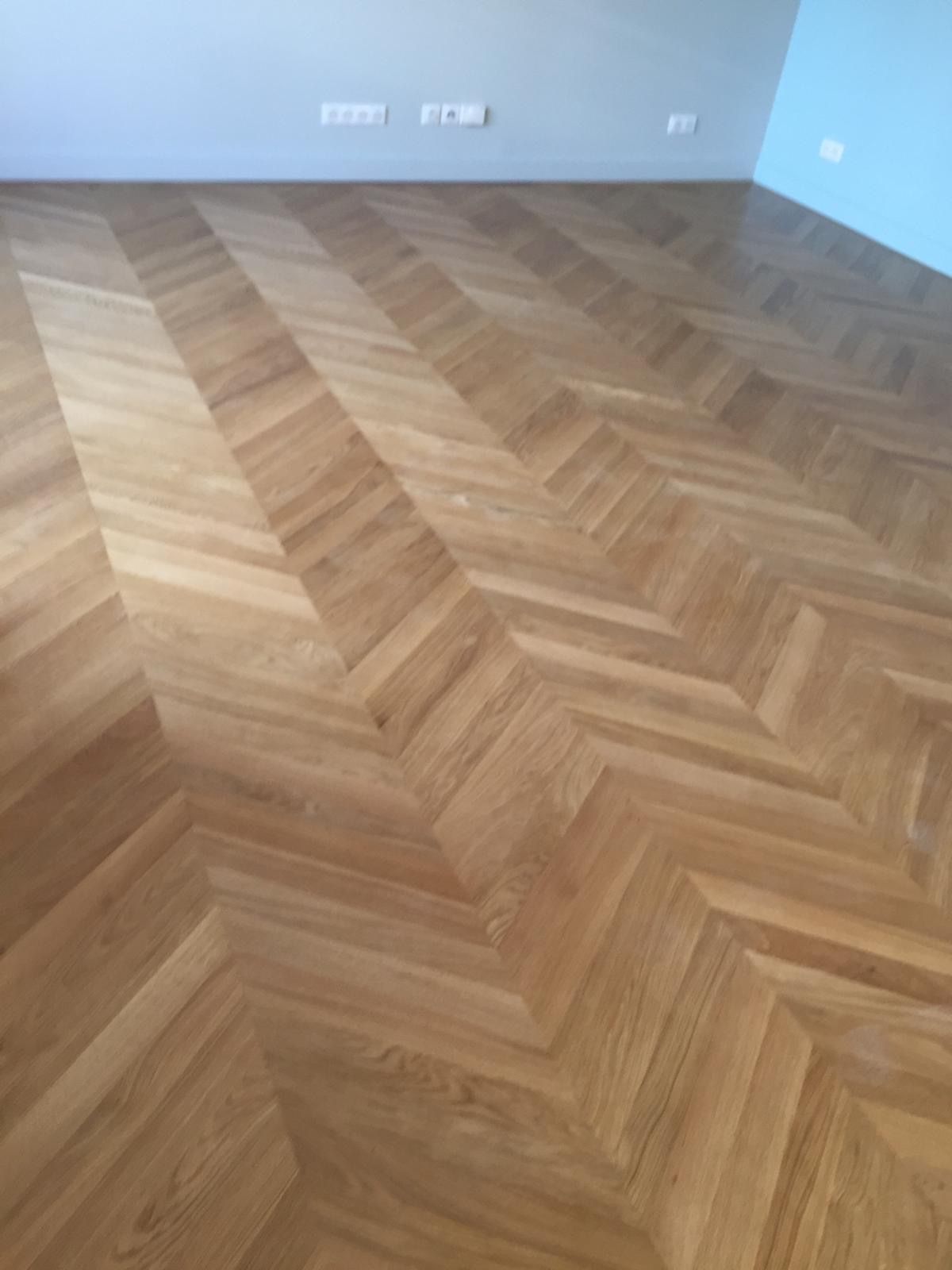 Pièce vide aux murs bleu clair et au parquet en chevrons.