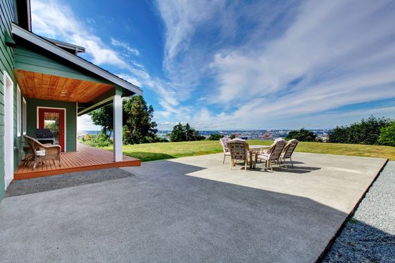 Terrasse avec coin repas extérieur attenante à une maison, donnant sur un jardin gazonné et un ciel bleu.