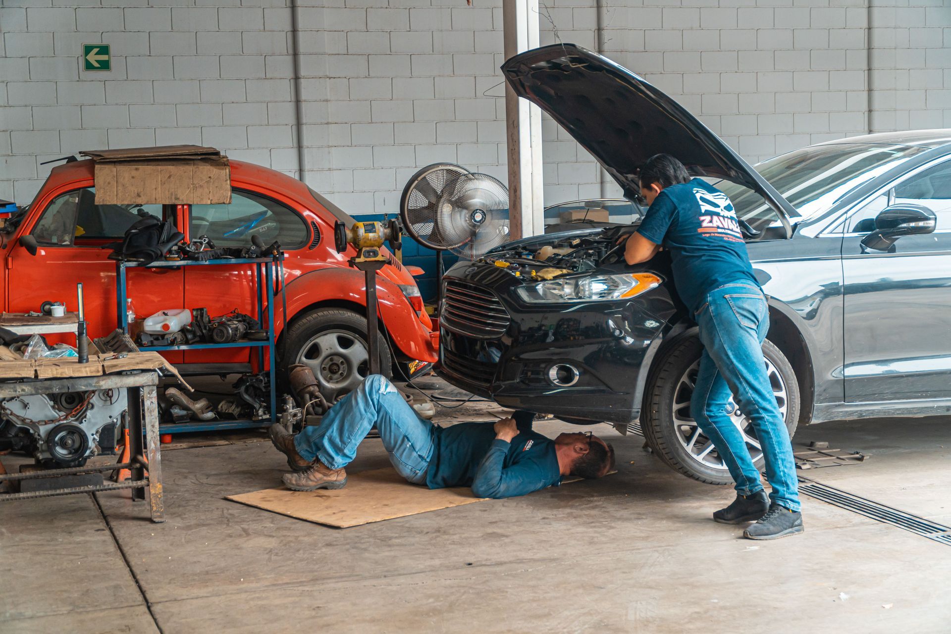 Des ouvriers d'un garage réparent une voiture argentée